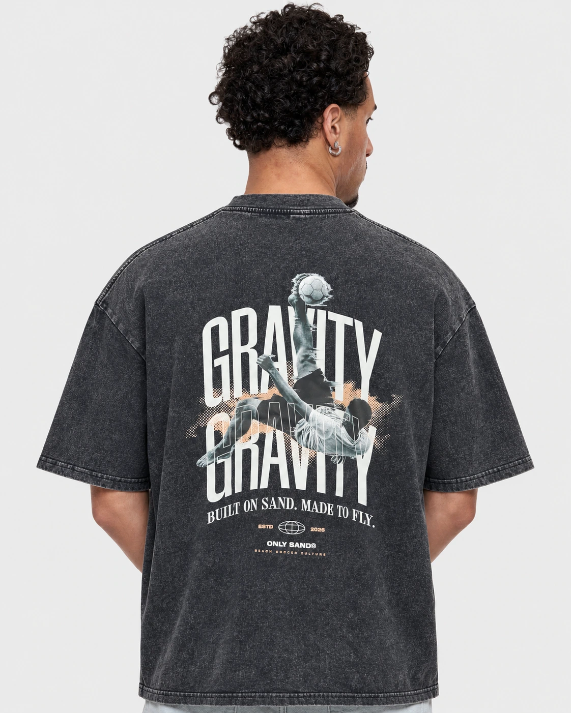 Back view of the GRAVITY washed charcoal-black T-shirt with an overhead-kick graphic and BUILT ON SAND. MADE TO FLY. slogan.